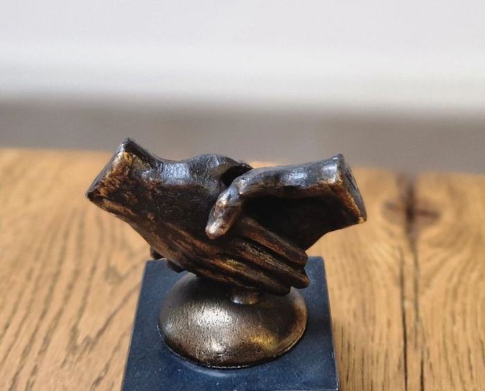 Bronzen beeldje van twee handen die elkaar schudden