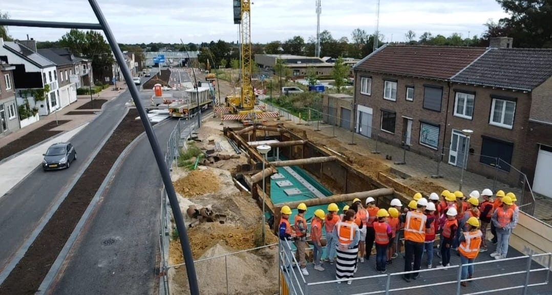 Groep jongeren op een uitkijkplatform boven een werkvak in de wijk