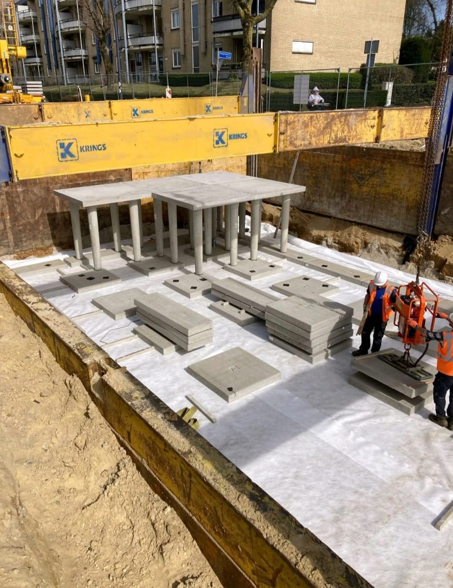 Betonnen elementen van een infiltratiekelder worden in een bouwkuip geplaatst