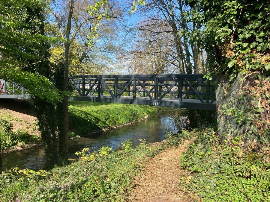 Beek met houten brug in een groen beekdal